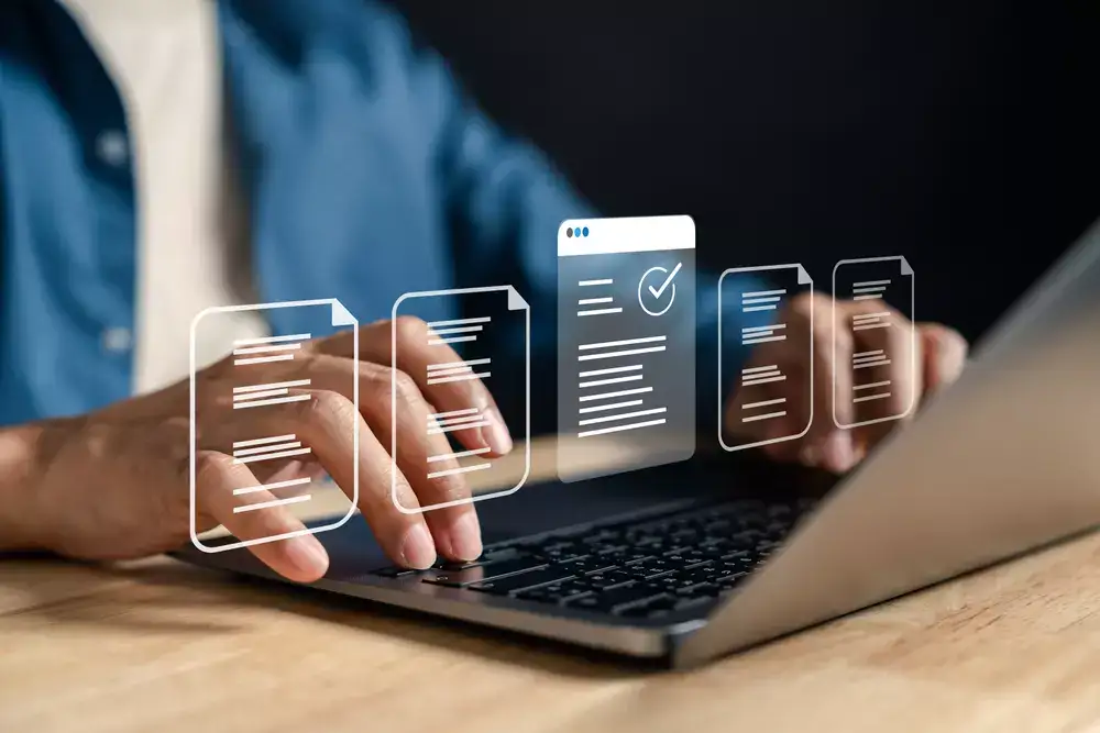 	
Pessoa atualizando conteúdo em um laptop com ícones de documentos digitais e marca de verificação, representando atualizações de conteúdo em plataforma digital.