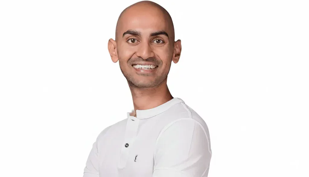 Neil Patel, especialista em marketing digital, sorrindo e usando camisa branca, imagem profissional otimizada para SEO com foco em Neil Patel.
